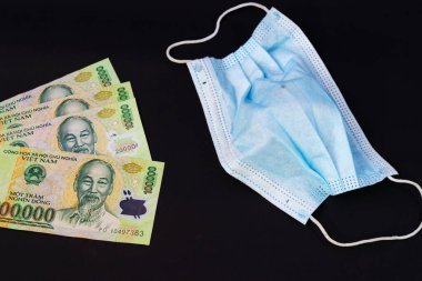 Vietnam Dong 'da para, VND Vietnamlı maskeli sağlık görevlisi kulak iltihabı ameliyatı ile karşı karşıya, insanlar sağlığına dikkat etsin ve koronavirüs hastalığını COVID-19 ve SMOG dumanı siyah arka planda PM2.5.