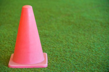 Kırmızı plastik küçük bir trafik, spor konisi küçük kapalı stadyumdaki yeşil çimenler ve bulanık arka plan için..