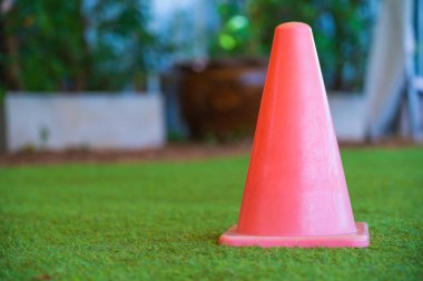 Kırmızı plastik küçük bir trafik, spor konisi küçük kapalı stadyumdaki yeşil çimenler ve bulanık arka plan için..