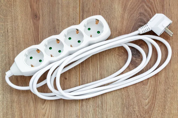 Cable de extensión de alimentación blanco de cuatro salidas en una superficie de madera . — Foto de Stock