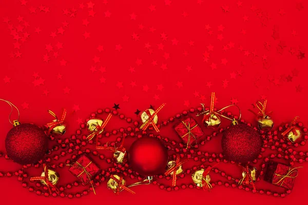 Kerstballen, geschenkdozen, gouden klokken en slinger op rood — Stockfoto