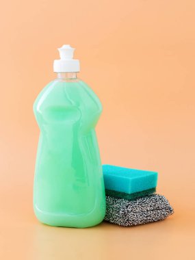 Plastik bir şişe ve süngerle yeşil bulaşık deterjanı.