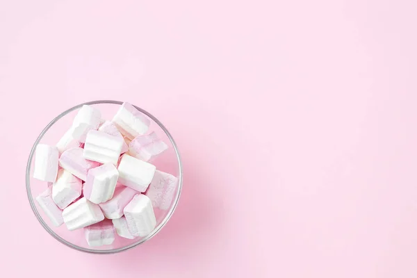 stock image Glass bowl with white pink fluffy marshmallows on a pastel pink 