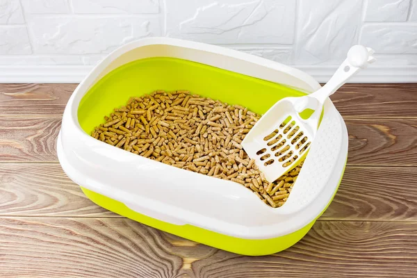 Yüksek kenarlı kedi kumu tepsisi ahşap topaklar ve kepçeyle.