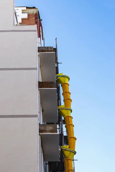 Hängende Teile einer gelben Plastikmüllrutsche. Bau. — Stockfoto