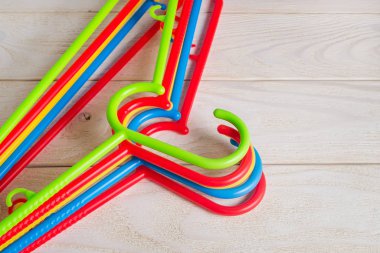 New multicolored plastic clothes hangers on a wooden surface.