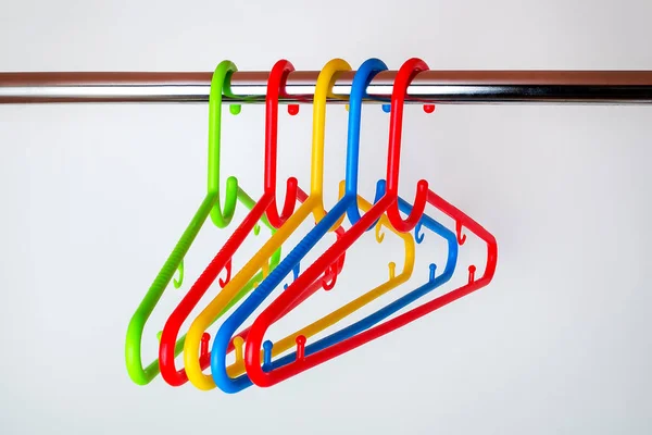 Пять разноцветных пластиковых вешалок для одежды на стержне в шкафу — стоковое фото