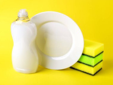 White dishwashing liquid, plate and three foam sponges.
