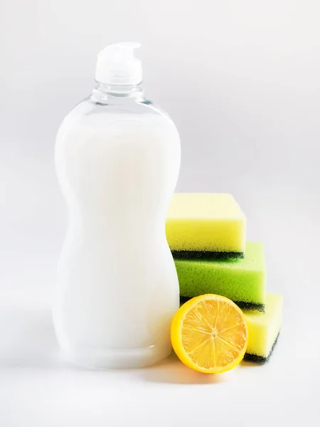 Líquido lavavajillas blanco, tres esponjas de espuma y limón . —  Fotos de Stock