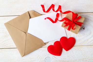 Kahverengi zarfta boş bir tebrik kartı, kırmızı kurdeleli hediye kutusu.