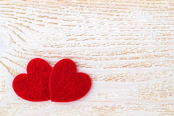 Δύο καρδιές με κόκκινη τσόχα σε λευκή επιφάνεια από ξύλο. — Φωτογραφία Αρχείου