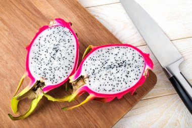 Ripe dragon fruit or pitaya cut in half on a wooden cutting board