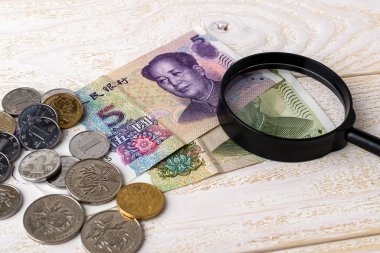 Çin Yuan banknotları üzerinde büyüteç ve ahşap bir yüzey üzerinde paralar