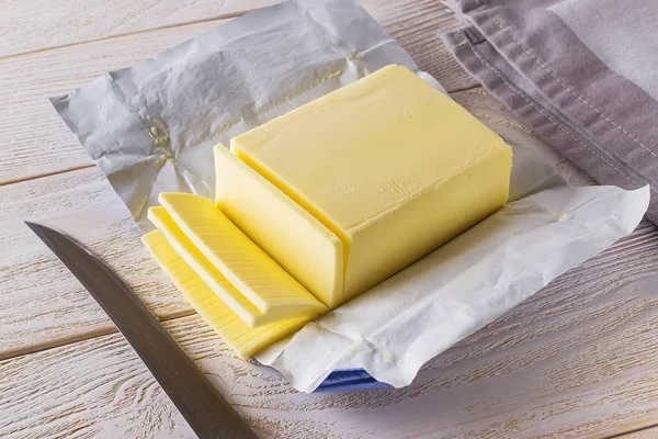 Kousky čerstvého žlutého másla uříznuté z právě otevřeného balení — Stock fotografie