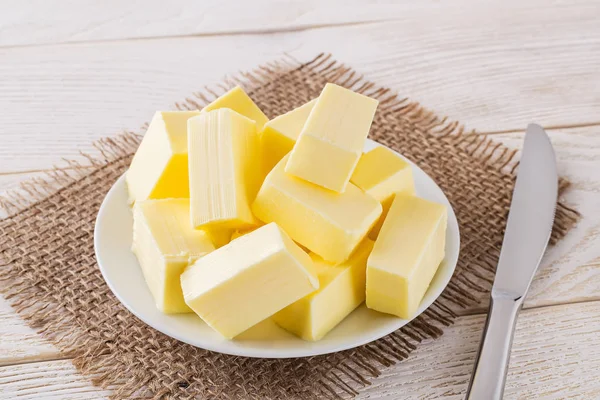 Prostokątne kawałki świeżego żółtego masła na białym spodku — Zdjęcie stockowe