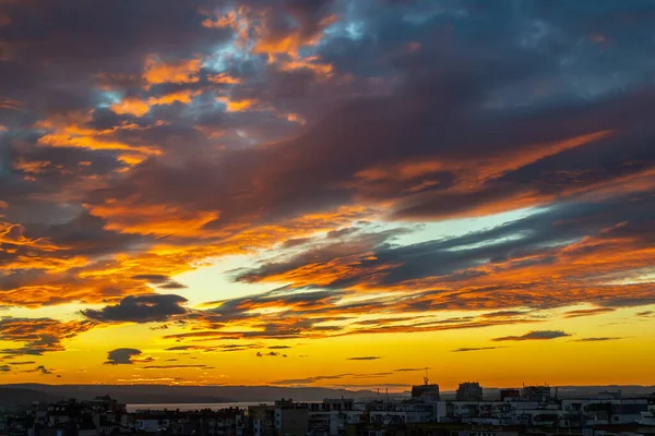 Fuego al atardecer en el cielo sobre una pequeña ciudad. Nubes azules oscuras con — Foto de Stock