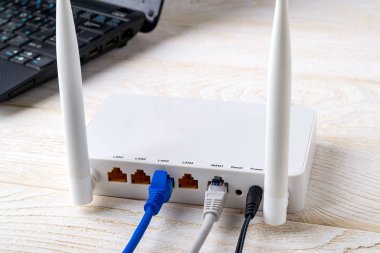 Dizüstü bilgisayarın yanındaki Wi-Fi yönlendiricisine bağlı ağ kabloları