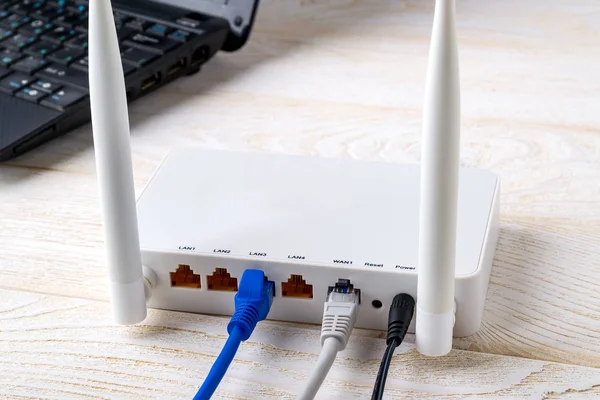 컴퓨터 근처에 있는 와이파이 라우터에 연결 된 네트워크 케이블 — 스톡 사진