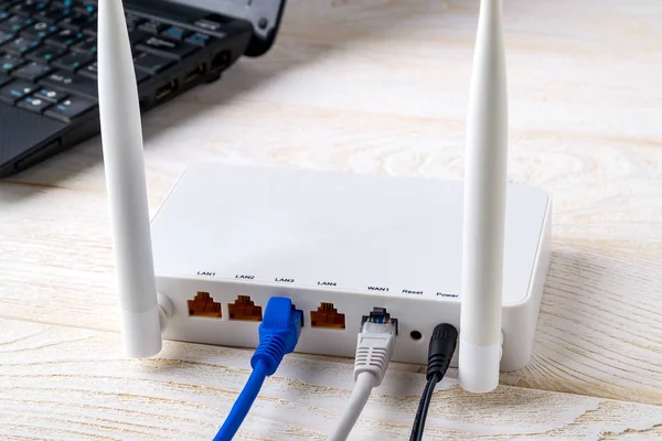 Dizüstü bilgisayarın yanındaki Wi-Fi yönlendiricisine bağlı ağ kabloları