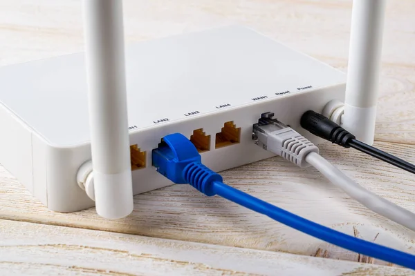 Крупним планом мережеві кабелі, з'єднані з білим Wi-Fi маршрутизатором — стокове фото