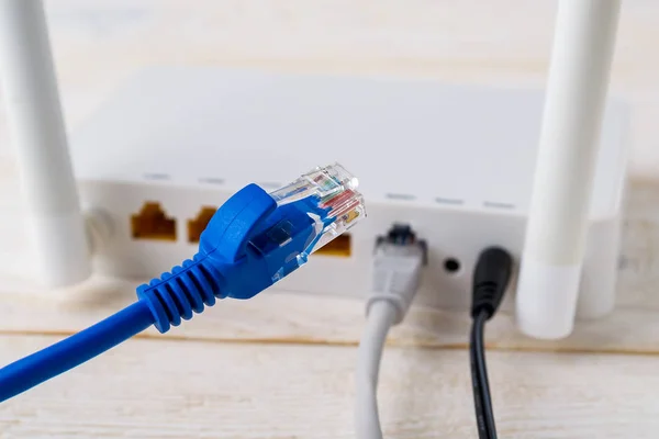 Bir Wi-Fi yönlendiricisinin arka planında mavi ağ kablosunun yakın plan görüntüsü
