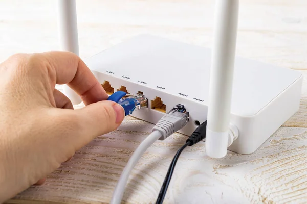 Mulher mão conectando um cabo de rede azul no roteador Wi-Fi — Fotografia de Stock