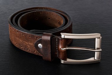 Siyah arka planda klasik metal tokalı hakiki deriden yapılmış kahverengi kuşak. Erkeklerin şık deri aksesuarları. Gösterişsiz görüntü. Ön görünüm.