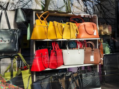 Varna, Bulgaristan, 27 Mart 2020. Güneşli bir bahar gününde bir tuhafiyecinin vitrininde modern moda sarı, kırmızı, beyaz ve kahverengi deri çantalar..