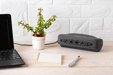 Beyaz ahşap bir masada dizüstü bilgisayarın yanında siyah hava iyonlaştırıcısı. Temiz hava almak için anyon jeneratörlü hava temizleyicisi ve ince tozu silmek, apartmanda ya da ofiste hoş olmayan kokular. Ön görünüm.