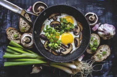 Kızarmış yumurta karanlık bir arka plan üzerinde bir tavada mantar ile.