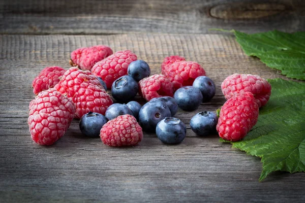 Frische Himbeeren und Blaubeeren auf Holztisch — Stockfoto