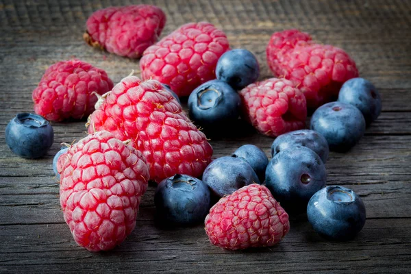 Frische Himbeeren und Blaubeeren auf Holztisch — Stockfoto