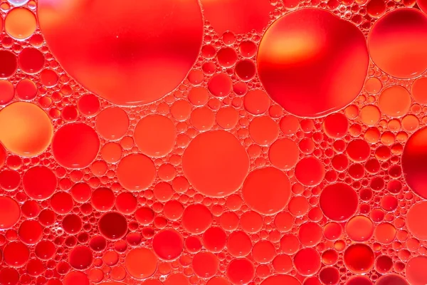 Oil drops in water on a red background — Stock Photo, Image