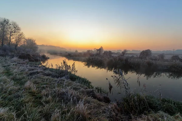 Ein schöner Sonnenaufgang über dem nebligen Fluss. — Stockfoto