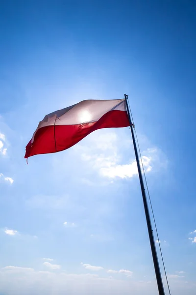 Old Polish flag against the sky.