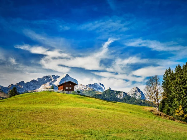 Chalet sur une prairie à la montagne Eckbauer avec les Alpes — Photo