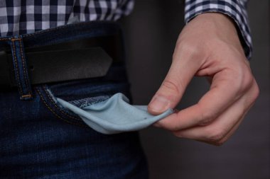 Kot pantolonlu, cebi boş bir iş adamı. Koyu gri arka planda işsiz, meteliksiz, iflas, kötü kredi, borç ve finansal konsept için boş kot cepleri gösteren genç adam