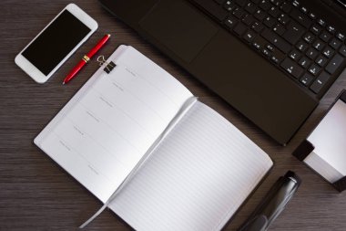 Akıllı telefonu, dizüstü bilgisayarı ve not defteri olan yenilikçi ofis masası. İş ve akıllı teknoloji kavramı, iş yerinde ya da evden dijital çalışma. Üst görünüm ofis masası