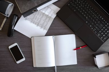Laptop, akıllı telefon, defter ve diğer malzemelerle modern ofis masası. Belgeler ve dijital cihazlarla ofis kavramı. Yeni yenilikçi Teknoloji ve verimli iş akışları