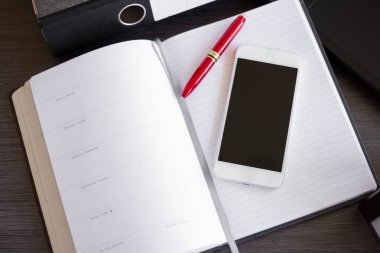 Akıllı telefonu kapat ve bir ofis masasının üzerine not defteri yaz. Bağlantı aygıtları için kavram. Yenilikçi Teknoloji ve Akıllı İş Çözümleri