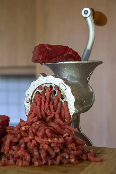 Old Manual meat grinder in a modern clean kitchen. Chopped and grinded raw meat in the process of making a meal. Background with copy space for text