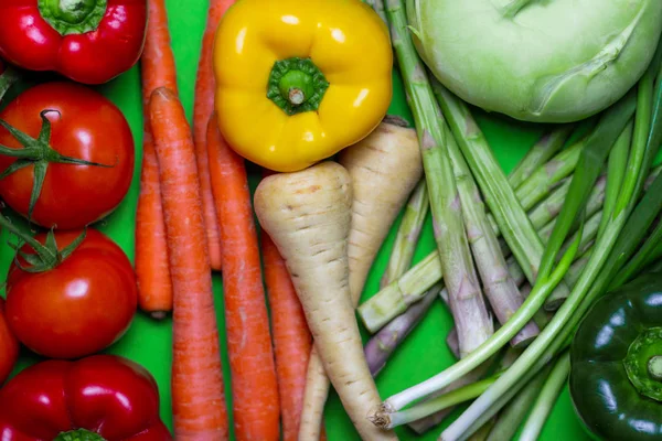 Colorful vegan Food spectrum Background. Organic and Fresh vegetables Concept. Food art rainbow. Tomatos, peppers, carrots, parsnip, green asparagus, leek, kohlrabies