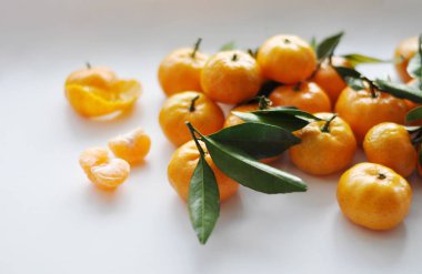 Beyaz arkaplanda yaprakları olan mandalinalar