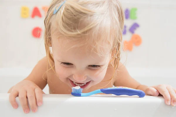 Улыбающаяся девушка с зубной щеткой в ванной комнате Лицензионные Стоковые Изображения