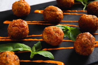 Fried potato cheese balls or croquettes with orange sauce and green salad. Selective focus