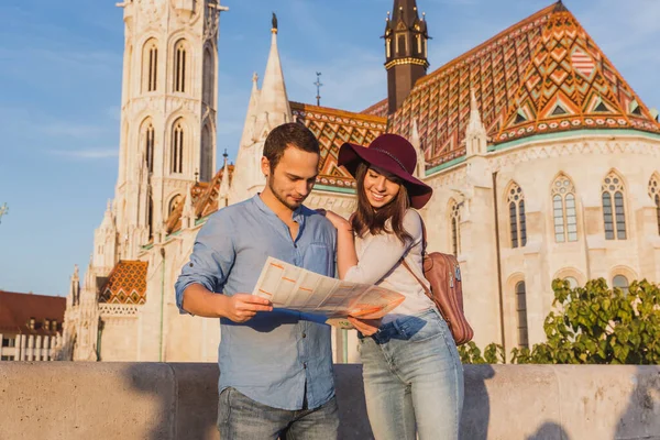 Young couple searching right direction on map from the point from Fisherman Bastion in Budapest with Matthias Church on background — Stockfoto