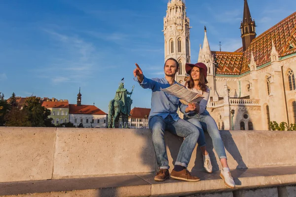 Young couple searching right direction on map from the point from Fisherman Bastion in Budapest with Matthias Church on background