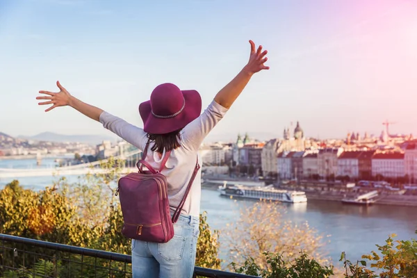 En glad ung kvinna njuter av sin resa till Budapest, Ungern från punkten från Gellert Hill under soluppgången på hösten under soluppgången. — Stockfoto