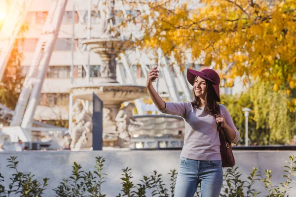 Una joven feliz tomar foto selfie cerca del ojo de Budapest gran noria rueda en Budapest —  Fotos de Stock