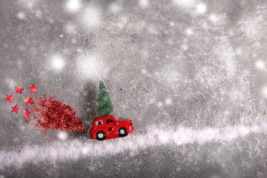 Noel oyuncağı kırmızı araba, çatıda köknar ağacı, kar yolu üzerinde kırmızı pullu duman..